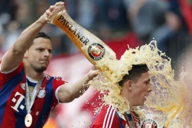 Bayern's Daniel van Buyten of Belgium, left, showers Pierre Hojbjerg of Denmark with beer after winning the German Soccer Championship after the season's last home game between FC Bayern Munich and VfB Stuttgart, in Munich, southern Germany, Saturday, May 10, 2014. (AP Photo/Matthias Schrader)